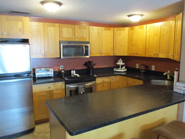 a kitchen with stainless steel appliances granite countertop a sink a stove and a refrigerator