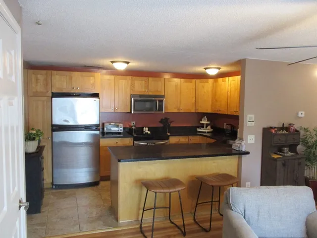 a kitchen with stainless steel appliances granite countertop a refrigerator a stove a sink a dining table and chairs