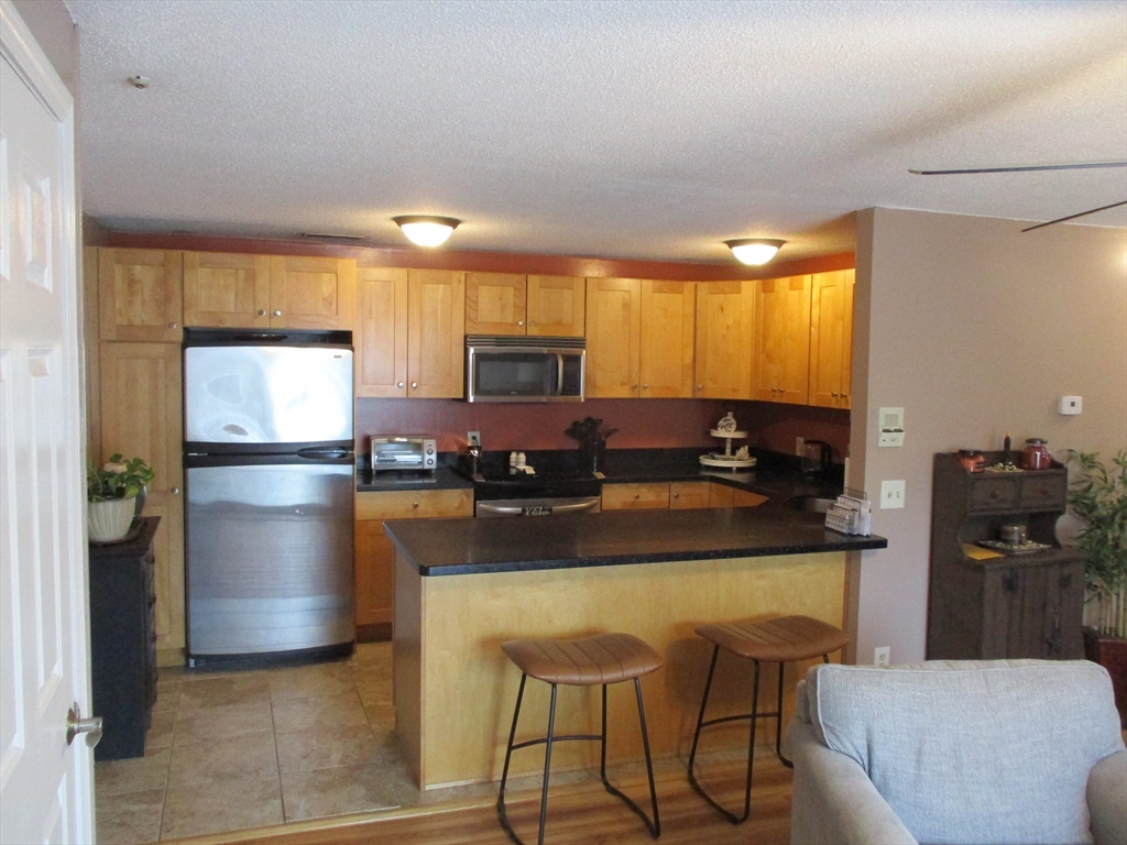 1475 Braley Road, Unit 21 New Bedford, MA 02745 - Photo 4 of 20 a kitchen with stainless steel appliances granite countertop a refrigerator a stove a sink a dining table and chairs
