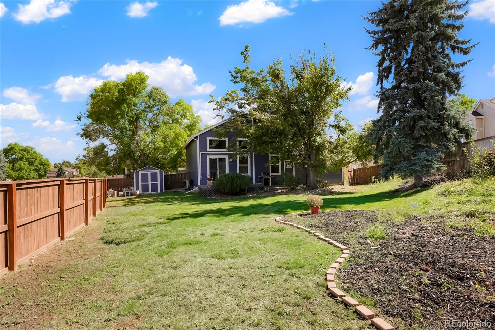 9191 Hickory Circle Highlands Ranch, CO 80126 - Photo 27 of 27 a backyard of a house with table and chairs plants and large trees