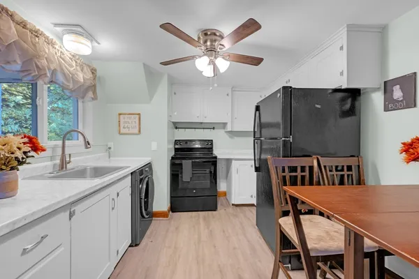 a kitchen with a refrigerator a sink dishwasher a dining table and chairs with wooden floor