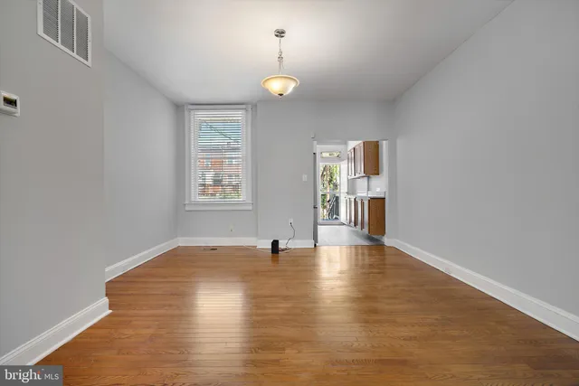 a view of an empty room with window and wooden floor