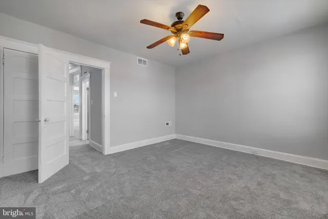 an empty room with a chandelier fan and a window