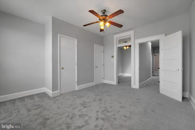 an empty room with closet and a ceiling fan