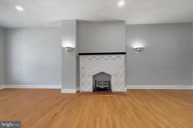 an empty room with wooden floor a fireplace and a window
