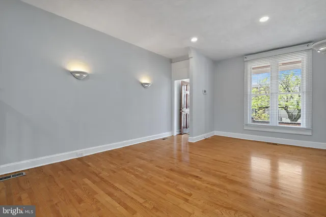 an empty room with wooden floor and window