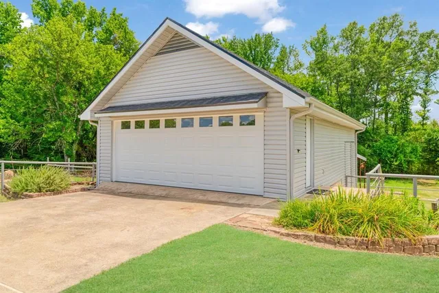 a view of a house with a yard plants and large tree