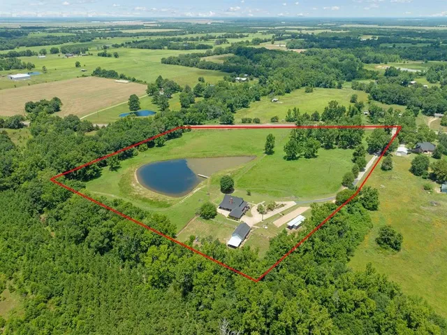 an aerial view of a residential houses with outdoor space and trees all around