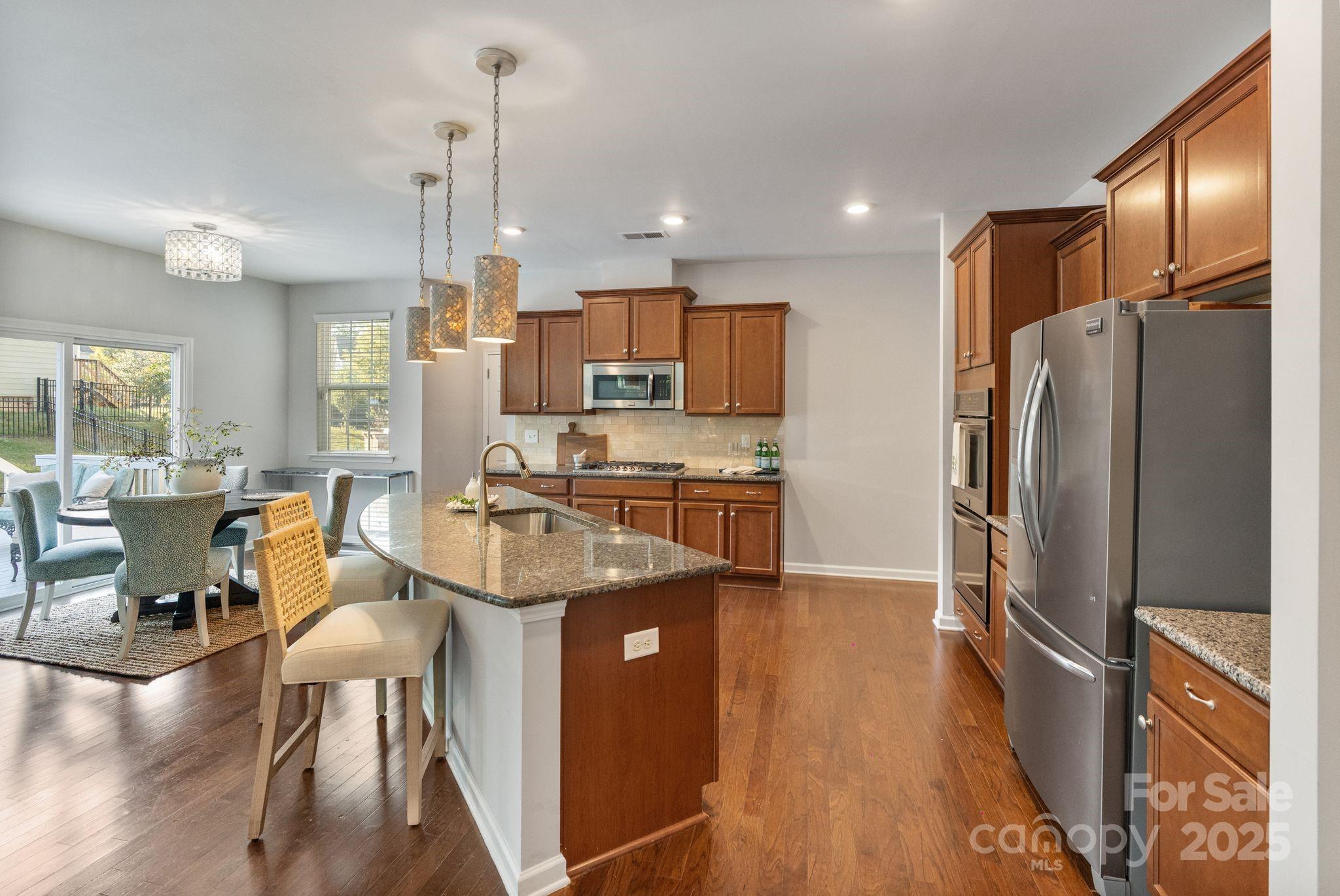 2005 Brightflower Lane York, SC 29745 - Photo 20 of 48 a kitchen with stainless steel appliances kitchen island granite countertop a refrigerator a stove a sink a dining table and chairs with wooden floor