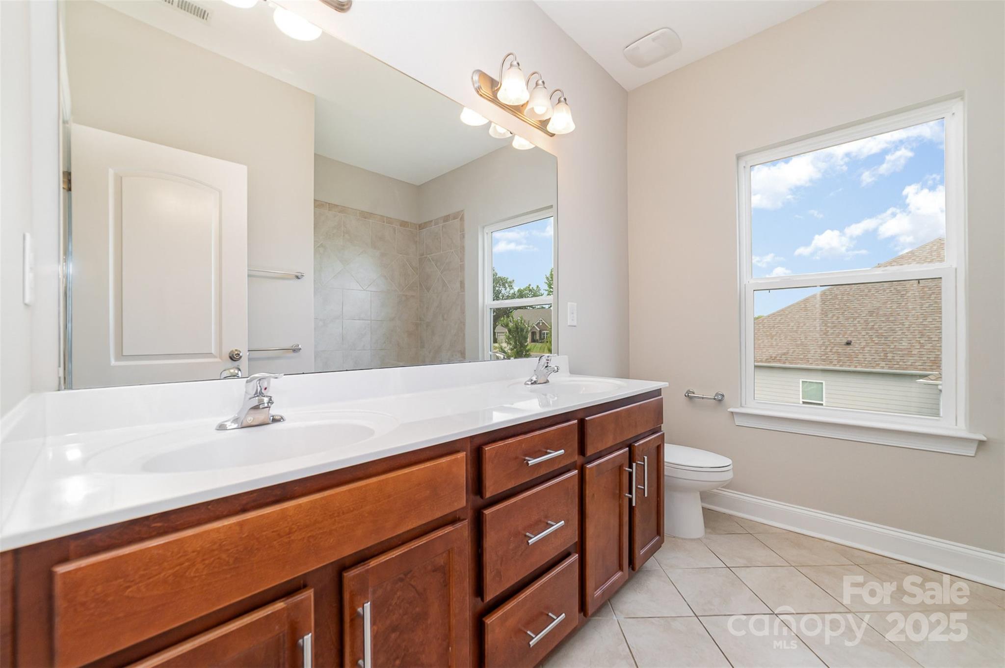 10024 Fox Trotter Lane Midland, NC 28107 - Photo 35 of 43 a bathroom with a granite countertop sink a toilet a mirror and a window