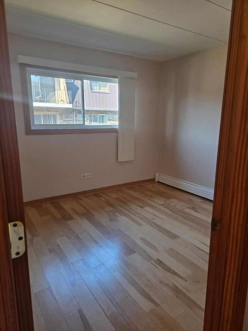 10510 Parkside Avenue, Unit 7 Chicago Ridge, IL 60415 - Photo 6 of 11 an empty room with wooden floor and windows