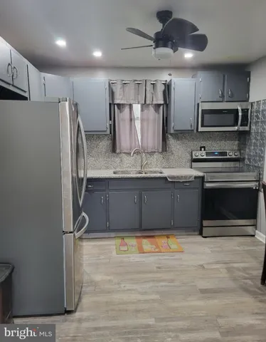 a large kitchen with stainless steel appliances granite countertop a stove a refrigerator and a sink