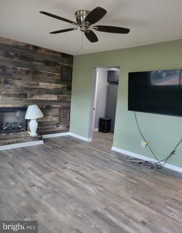 a view of an empty room with wooden floor and a ceiling fan