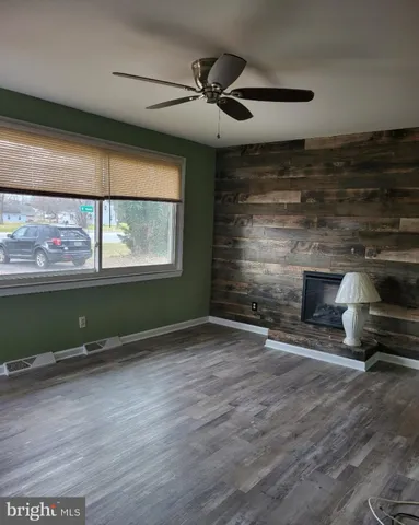 an empty room with wooden floor a fireplace and windows