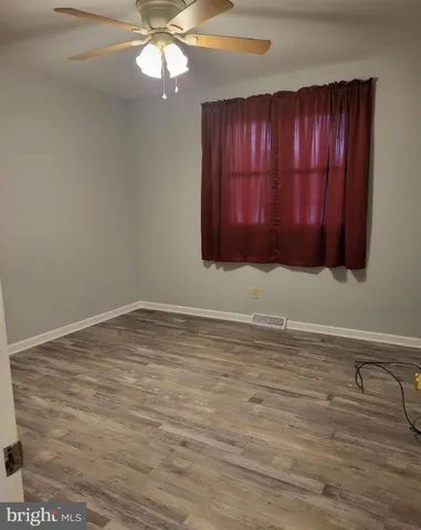 a view of an empty room with window and wooden floor