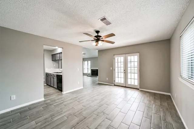 a view of an empty room with a window and wooden floor