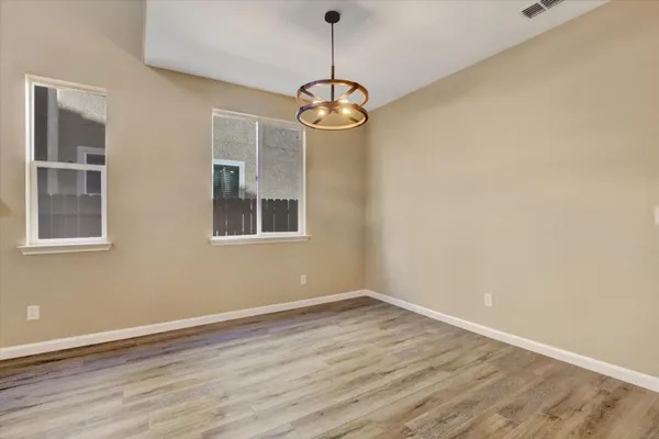 a view of an empty room with window and wooden floor