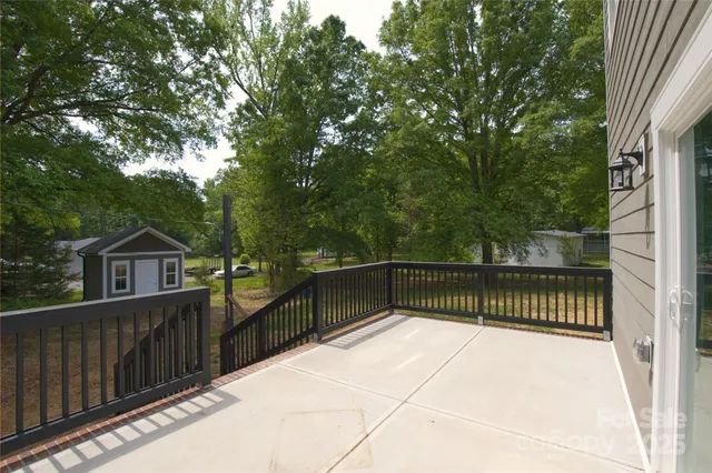 a view of a roof deck with wooden fence and large trees