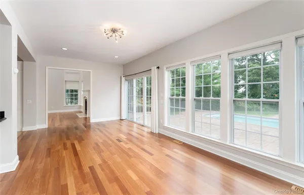 a view of empty room with wooden floor and fan
