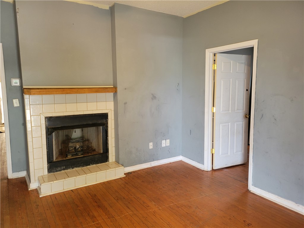 1208 East Main Street Seneca, SC 29678 - Photo 7 of 19 This inviting space features warm hardwood flooring and a classic fireplace, perfect for cozy evenings.