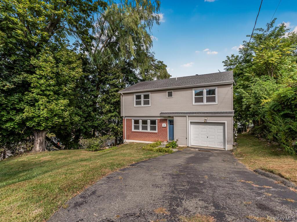 25 Midway Road White Plains, NY 10607 - Photo 1 of 1 View of front of property featuring driveway, a front lawn, a garage, brick siding, and view of wooded area