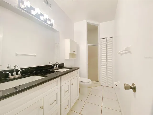 a bathroom with a granite countertop sink a toilet and a mirror