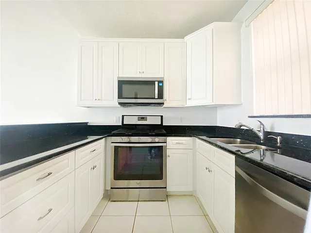 a kitchen with granite countertop white cabinets and appliances