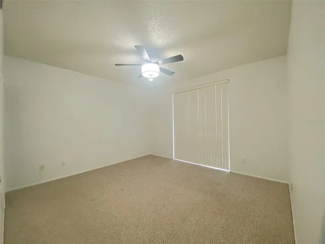 an empty room with a ceiling fan and a window