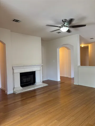a view of an empty room with wooden floor fireplace and a window