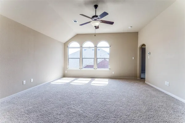 an empty room with windows and ceiling fan