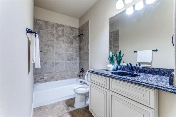 a bathroom with a granite countertop sink a toilet and bathtub