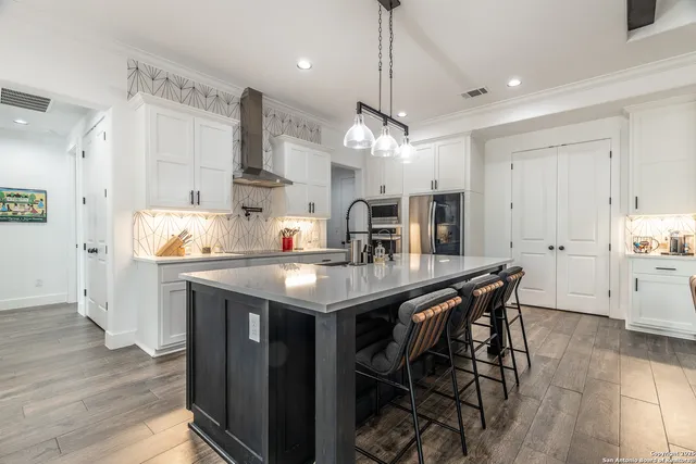 a kitchen with stainless steel appliances a table chairs refrigerator and microwave