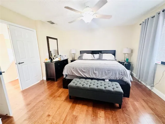 a bedroom with a bed and a large window with wooden floor