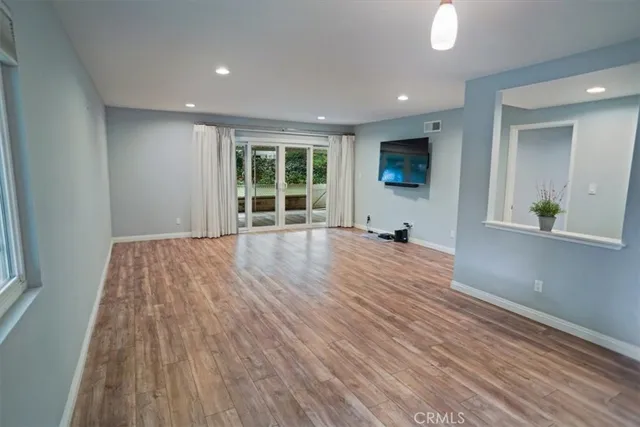 an empty room with wooden floor and windows