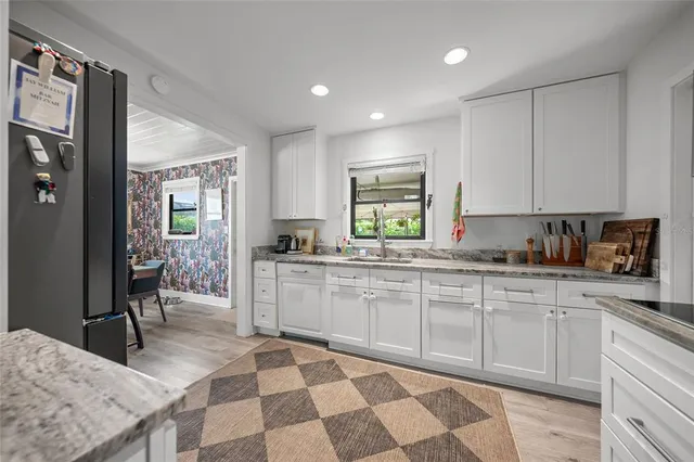 a kitchen with stainless steel appliances granite countertop white cabinets and window