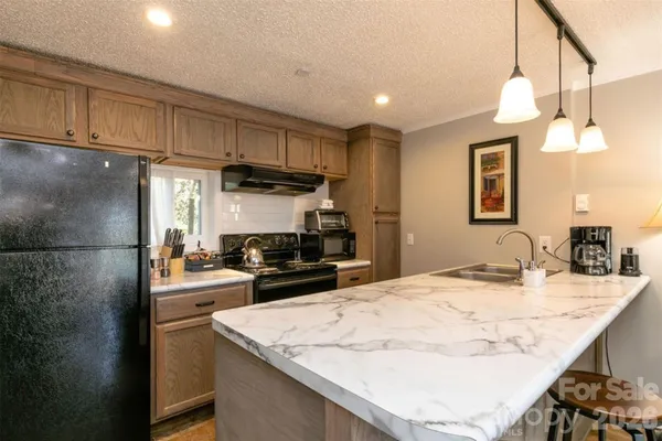 a kitchen with kitchen island granite countertop a sink stove and refrigerator