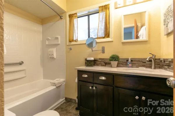 a bathroom with a granite countertop sink a toilet and shower