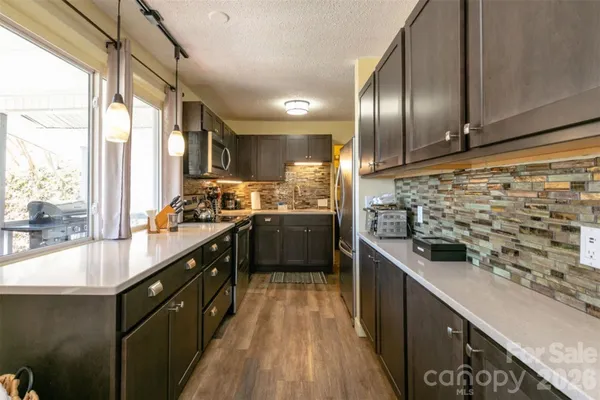 a kitchen with stainless steel appliances a sink a counter top space a large window and stainless steel appliances