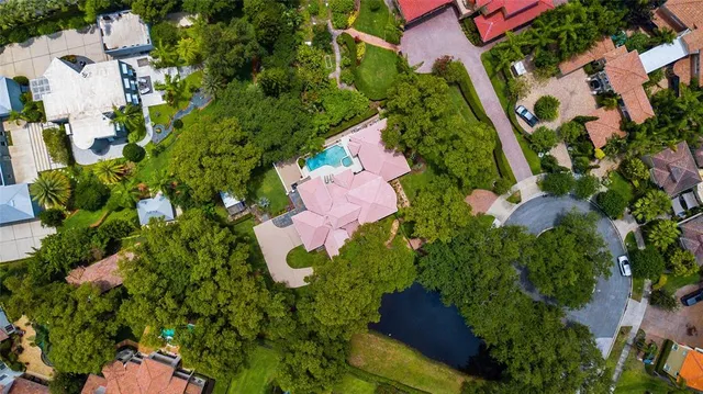 an aerial view of residential house with outdoor space and trees all around