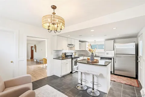 a kitchen with stainless steel appliances granite countertop a refrigerator a stove top oven a sink dishwasher and white cabinets with wooden floor