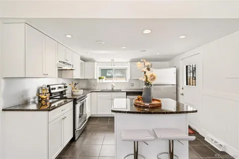 a kitchen with stainless steel appliances granite countertop a stove a sink and white cabinets