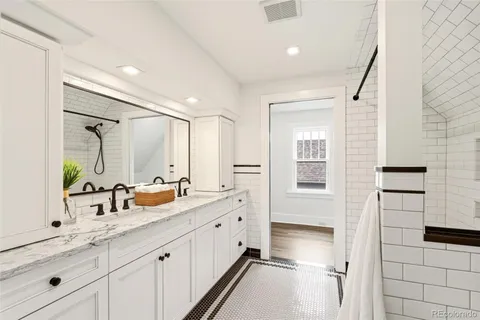 a spacious bathroom with a double vanity sink a large mirror and shower