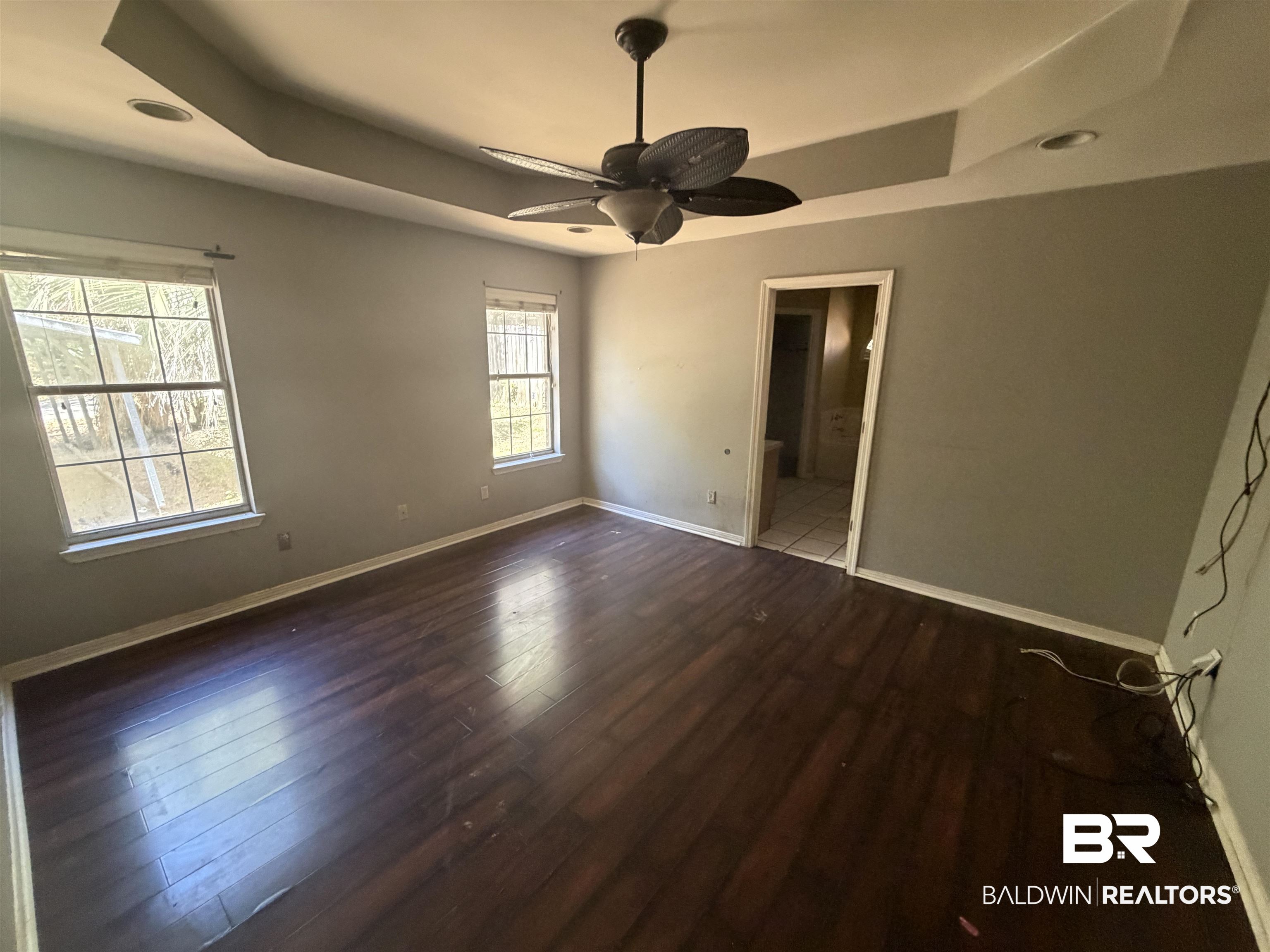 7067 Pinehill Road Daphne, AL 36526 - Photo 15 of 18 Unfurnished bedroom with a raised ceiling, dark wood finished floors, a ceiling fan, and connected bathroom