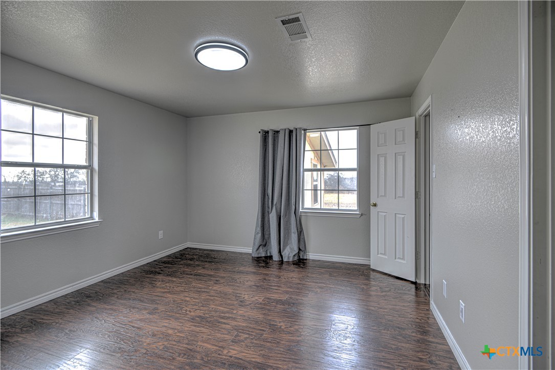 809 Hudson Lane Eddy, TX 76524 - Photo 24 of 48 an empty room with wooden floor and windows