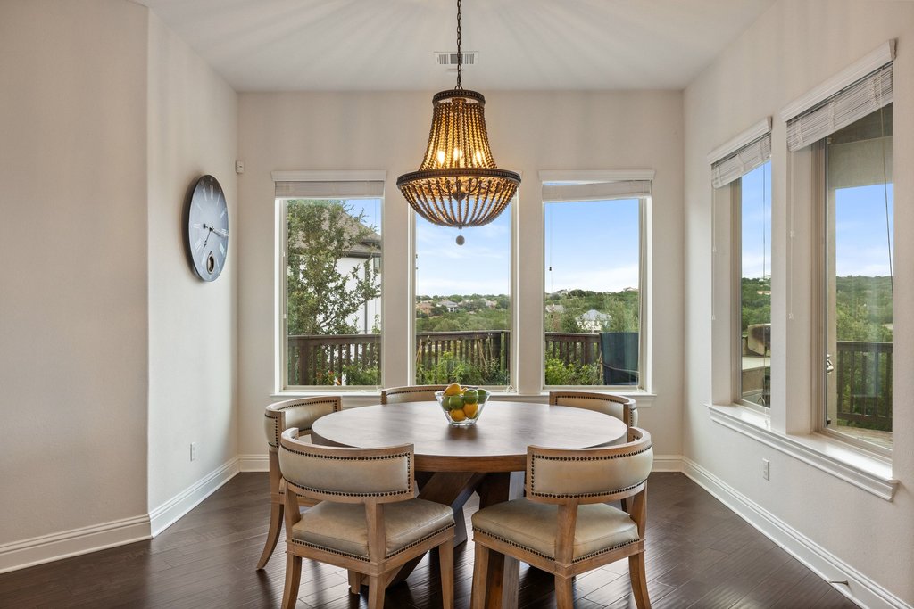 215 Lodestone Lane Austin, TX 78738 - Photo 17 of 40 A refined dining space with panoramic views of the verdant landscape and an elegant chandelier.