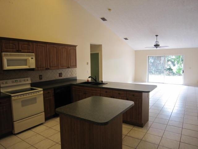 7408 Shell Ridge Terrace Lake Worth, FL 33467 - Photo 10 of 23 a kitchen with granite countertop a sink a stove top oven and cabinets