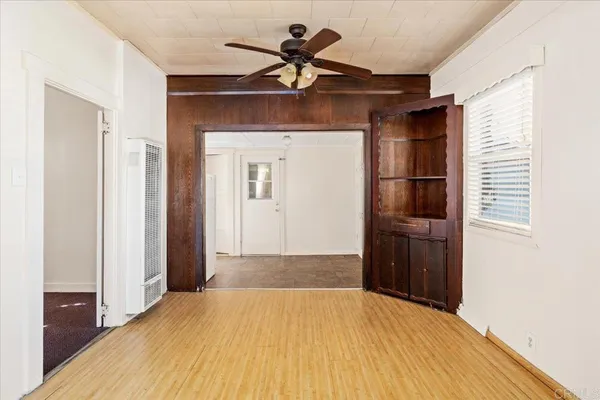a view of empty room with wooden floor and fan