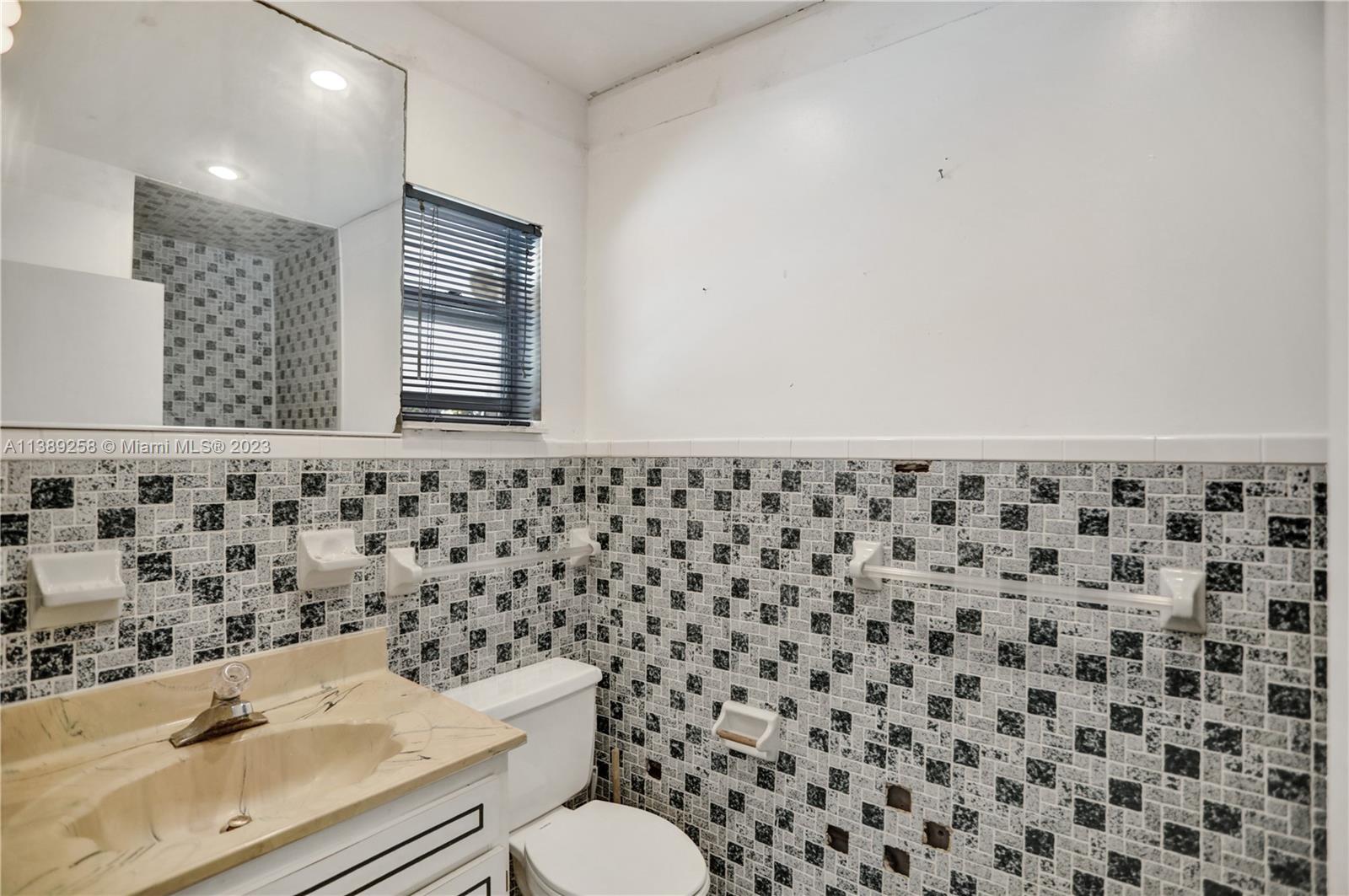 837 Washington Street Hollywood, FL 33019 - Photo 16 of 65 a bathroom with a granite countertop toilet a sink and a mirror