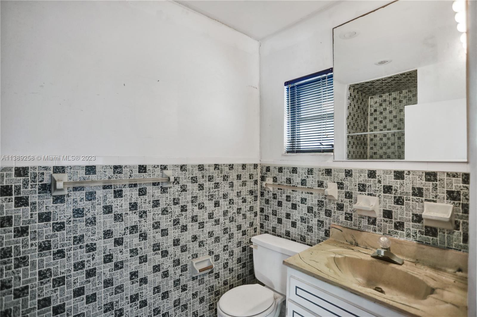 837 Washington Street Hollywood, FL 33019 - Photo 18 of 65 a bathroom with a granite countertop toilet and a sink