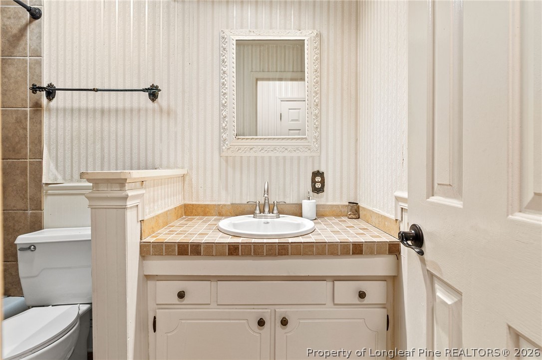 5605 MacGregor Court Fayetteville, NC 28304 - Photo 31 of 49 a bathroom with a granite countertop sink a toilet and mirror